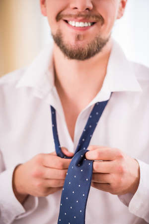 Young businessman dressed to work and choice of tie at homeの写真素材