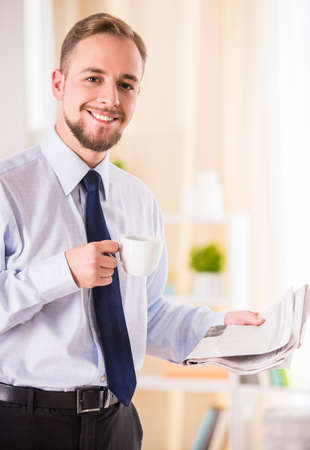 Young businessman drinking coffee and reading the newspaperの写真素材