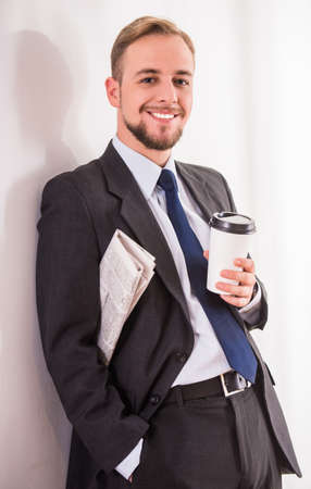 Young businessman drinking coffee and reading the newspaperの写真素材