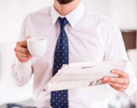 Young businessman drinking coffee and reading the newspaperの写真素材