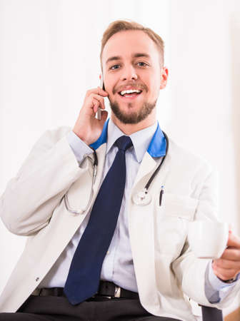 Portrait of tired young doctor in a white coat on a white backgroundの写真素材