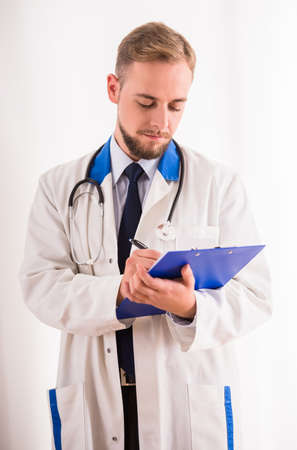 Portrait of tired young doctor in a white coat on a white backgroundの写真素材