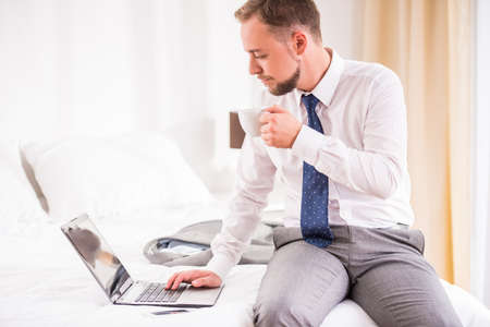 Young businessman dressed to work and use the laptop in the bedroom at homeの写真素材