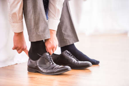 Young businessman dress shoes in the bedroom at homeの写真素材