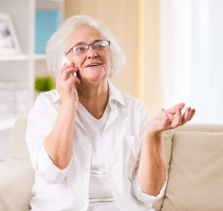 Portrait of senior woman sitting on the couch at homeの写真素材