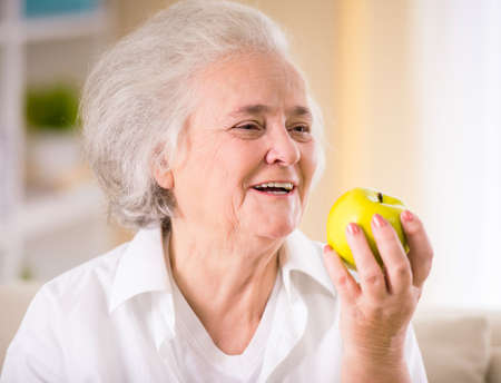 Portrait of senior woman sitting on the couch at homeの写真素材
