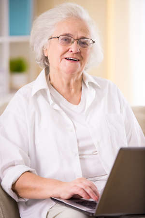 Portrait of senior woman sitting on the couch at homeの写真素材