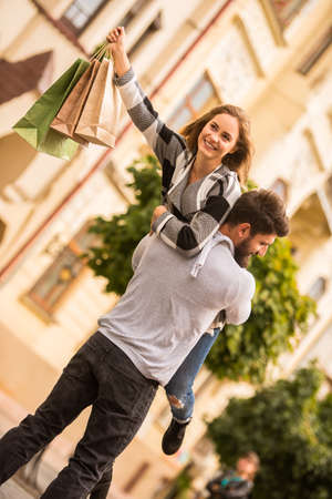 Young happy couple with shopping bags while walking in the cityの写真素材