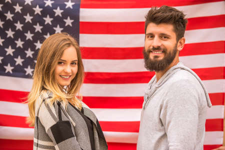 Portrait of a young happy couple on the background of the US flagの写真素材