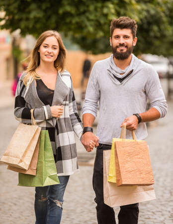 Young happy couple with shopping bags while walking in the cityの写真素材