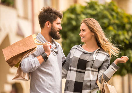 Young happy couple with shopping bags while walking in the cityの写真素材