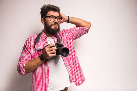 Young cheerful photographer with beard, while working in studioの写真素材