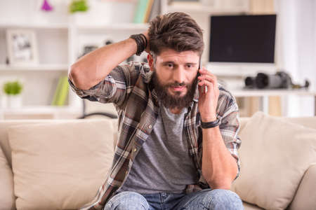 Young cheerful photographer with beard, while working in his officeの写真素材