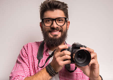 Young cheerful photographer with beard, while working in studioの写真素材