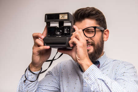 Young cheerful photographer with beard, while working in studioの写真素材