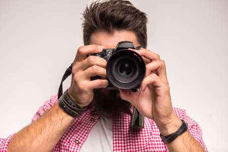 Young cheerful photographer with beard, while working in studioの写真素材