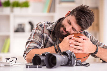 Young cheerful photographer with beard, while working in his officeの写真素材