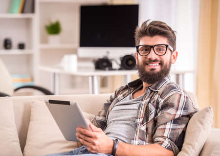 Young cheerful photographer with beard, while working in his officeの写真素材