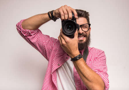 Young cheerful photographer with beard, while working in studioの写真素材