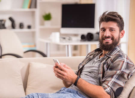 Young cheerful photographer with beard, while working in his officeの写真素材