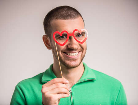 Portrait of a young man with glasses in the form of heartの写真素材