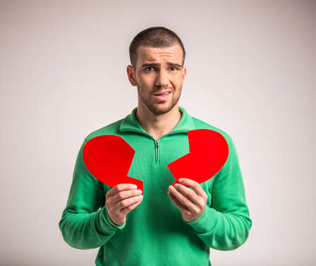 Portrait of a young man holding a large paper heart to his girlfriendの写真素材