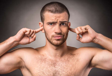 Portrait of an emotional young man with a naked torso on a black backgroundの写真素材