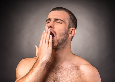Portrait of an emotional young man with a naked torso on a black backgroundの写真素材