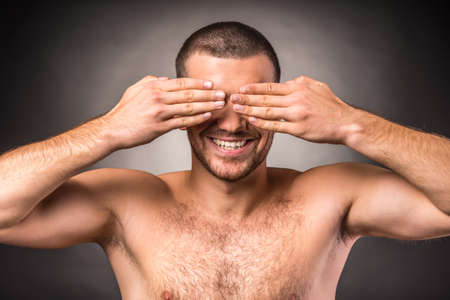 Portrait of an emotional young man with a naked torso on a black backgroundの写真素材