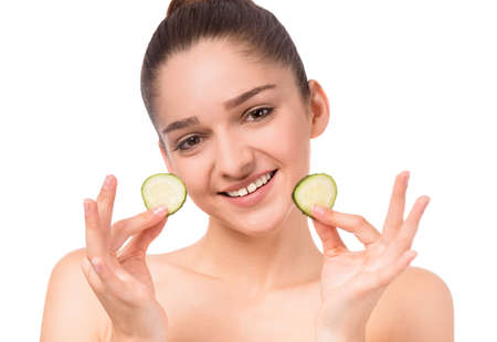 Portrait of a young beautiful woman with cucumber, isolated on a white backgroundの写真素材