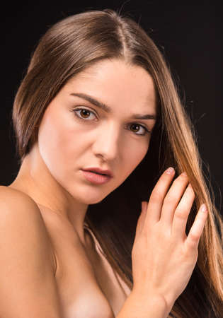 Portrait of a young beautiful woman with long hair, isolated on black backgroundの写真素材