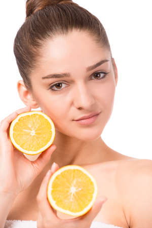 Portrait of a young beautiful woman with orange, isolated on a white backgroundの写真素材