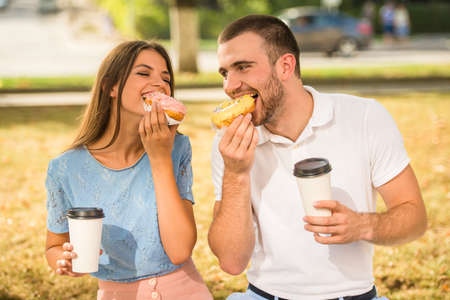 Loving young couple on a date in the park and drink coffeeの写真素材