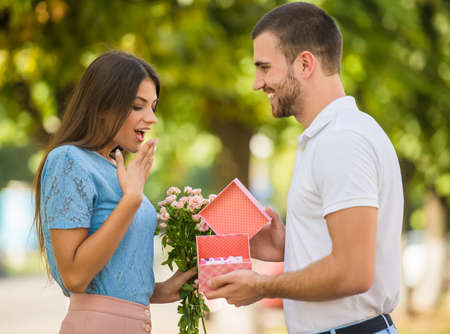 Loving young couple on a date with flowers in the parkの写真素材