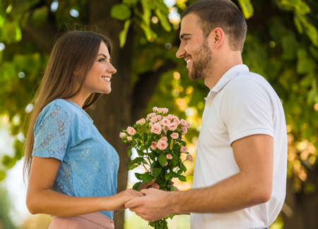 Loving young couple on a date with flowers in the parkの写真素材
