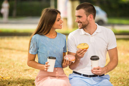 Loving young couple on a date in the park and drink coffeeの写真素材