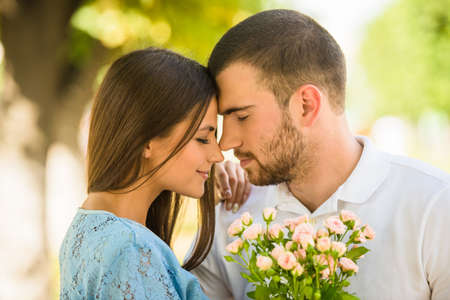 Loving young couple on a date with flowers in the parkの写真素材