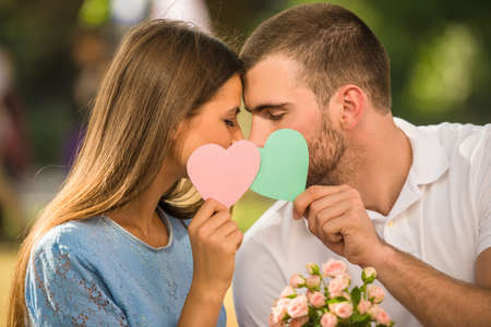 Loving young couple on a date with flowers and with a gift in the parkの写真素材