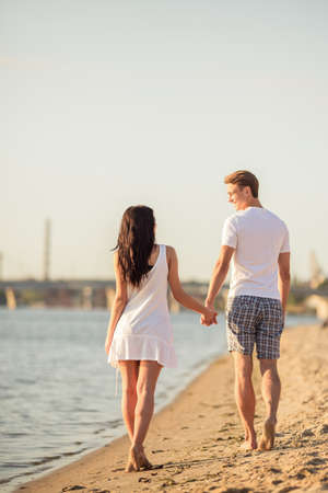Loving young couple walk on the beach in summerの写真素材