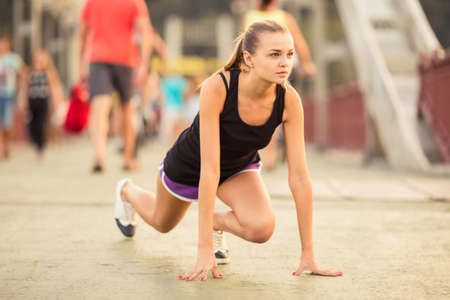 The young beautiful girl with headphones running and doing fitness in cityの写真素材