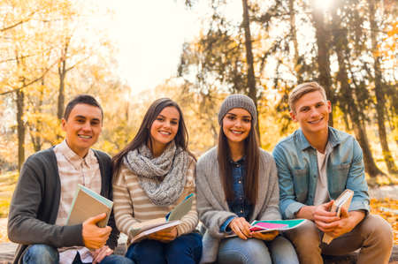 Group of young people students while walking autumn parkの写真素材