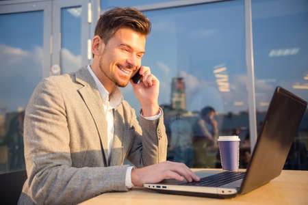 The young successful businessman, sitting at a table in his office using laptopの写真素材