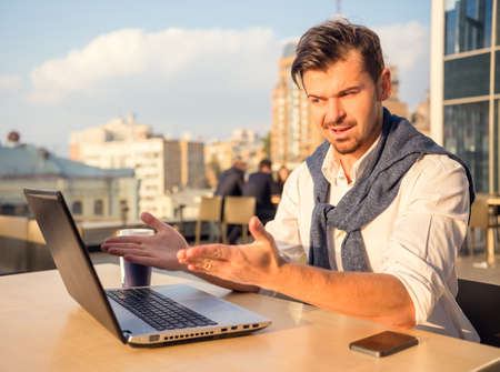 The young successful businessman, sitting at a table in his office using laptopの写真素材