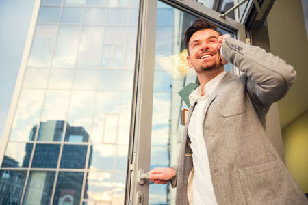 Young successful businessman talking on the phone in the background office centerの写真素材