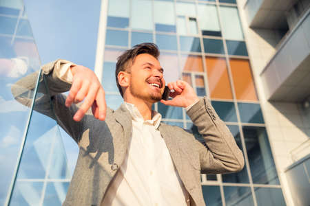 Young successful businessman talking on the phone in the background office centerの写真素材