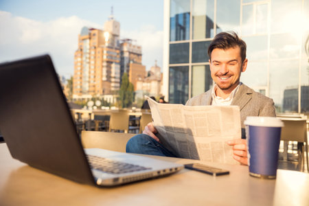 The young successful businessman, sitting at a table in his office using laptopの写真素材