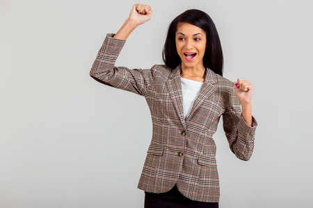 Beautiful young African American woman expressing their emotions in a studio on a gray backgroundの写真素材