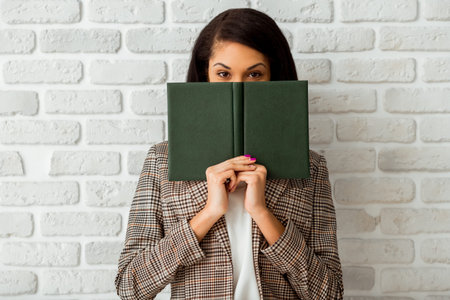 Beautiful African American women writing in a notebook on a gray background