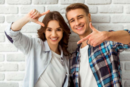Beautiful young couple in love expressing their emotions on the brick wall backgroundの写真素材