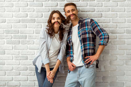 Beautiful young couple in love expressing their emotions on the brick wall backgroundの写真素材